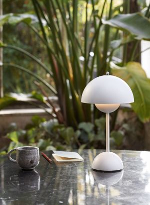 Flowerpot VP9 oppladbar bordlampe H30 fra Tradition i matt hvit. Plassert på et sort bord ute, lys på