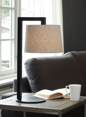 Sibyl bordlampe i sort fra Høvik lys med beige skjerm. plassert på et sidebord, lys på