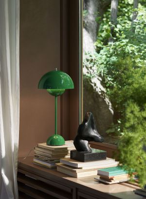 Flowerpot VP3 bordlampe H50 fra Tradition i grønn. Plassert oppå en vinduskarm sammen med bøker. lys på