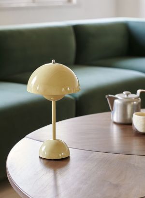 Flowerpot VP9 oppladbar bordlampe H30 fra Tradition i lysegul. Plassert på et stuebord foran en grønn sofa. lys av