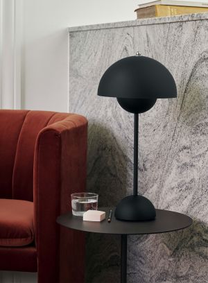 Flowerpot VP3 bordlampe H50 fra Tradition i matt sort. Plassert på et rundt sidebord ved siden av en rød sofa. lys av