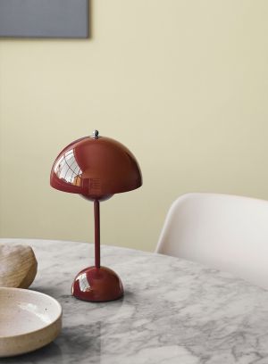Flowerpot VP9 oppladbar bordlampe H30 fra Tradition i rødbrun. Plassert oppå et hvitt spisebord. Lys av