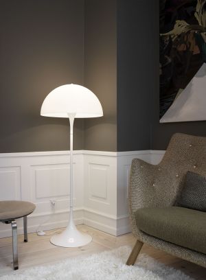Panthella gulvlampe fra Louis Poulsen i hvit. Plassert foran en bokhylle, lys på
