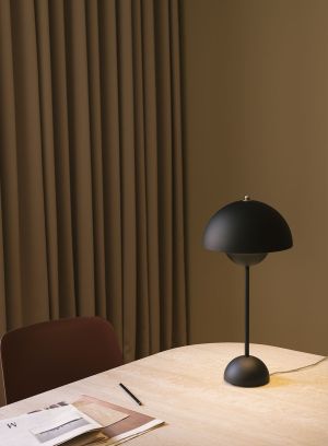Flowerpot VP3 bordlampe H50 fra Tradition i matt sort. Plassert på et rundt sidebord ved siden av en rød sofa. lys av