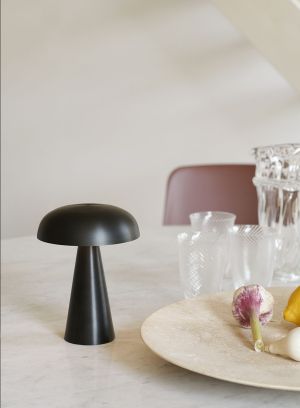 Como SC53 oppladbar bordlampe fra Tradition i sort. plassert oppå et spisebord ved siden av servise. lys av