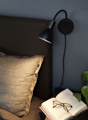 Bent vegglampe fra Høvik lys med svart skjerm. Montert til vegg, lys på