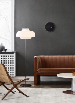 Copenhagen SC14 gulvlampe fra Tradition i sort med hvit skjerm. plassert mellom en oransje sofa og en stol. lys på