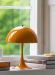 Panthella mini bordlampe fra Louis Poulsen i oransje, lys på