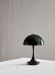 Panthella 160 oppladbar bordlampe i sort på et bord. Foto