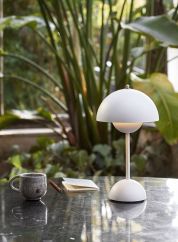 Flowerpot VP9 oppladbar bordlampe H30 fra Tradition i matt hvit. Plassert på et sort bord ute, lys på