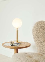 Miira bordlampe nordic gold/opal på et sofabord med lyset tent. 