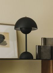Flowerpot VP9 oppladbar bordlampe H30 fra Tradition i matt sort. Plassert på en hylle, lys av