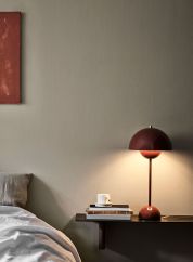 Flowerpot VP3 bordlampe H50 fra Tradition i rødbrun farge. Plassert på en hylle ved siden av en seng. lys på