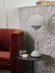 Flowerpot VP3 bordlampe H50 fra Tradition i matt grå. Plassert på et sort rundt sidebord ved siden av en rød sofa. lys av