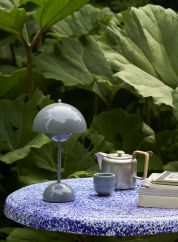 Flowerpot VP9 oppladbar bordlampe - stone blue ute på et bord på balkongen