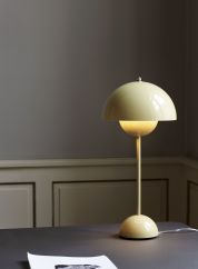 Flowerpot VP3 bordlampe H50 fra Tradition i lysegul. Plassert oppå et sort bord, lys på
