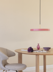 Asteria taklampe fra Umage i rosa. Henger over et rundt bord med stol ved siden av. lys av