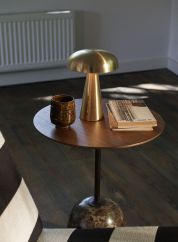 Como SC53 oppladbar bordlampe fra Tradition i gullfarge. plassert ved siden av tre glass. lys av 