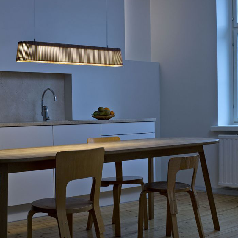En avlang taklampe lyser ned på et langt kjøkkenbord