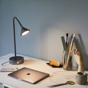 En bordlampe lyser ned på en bærbar laptop på skrivepulten